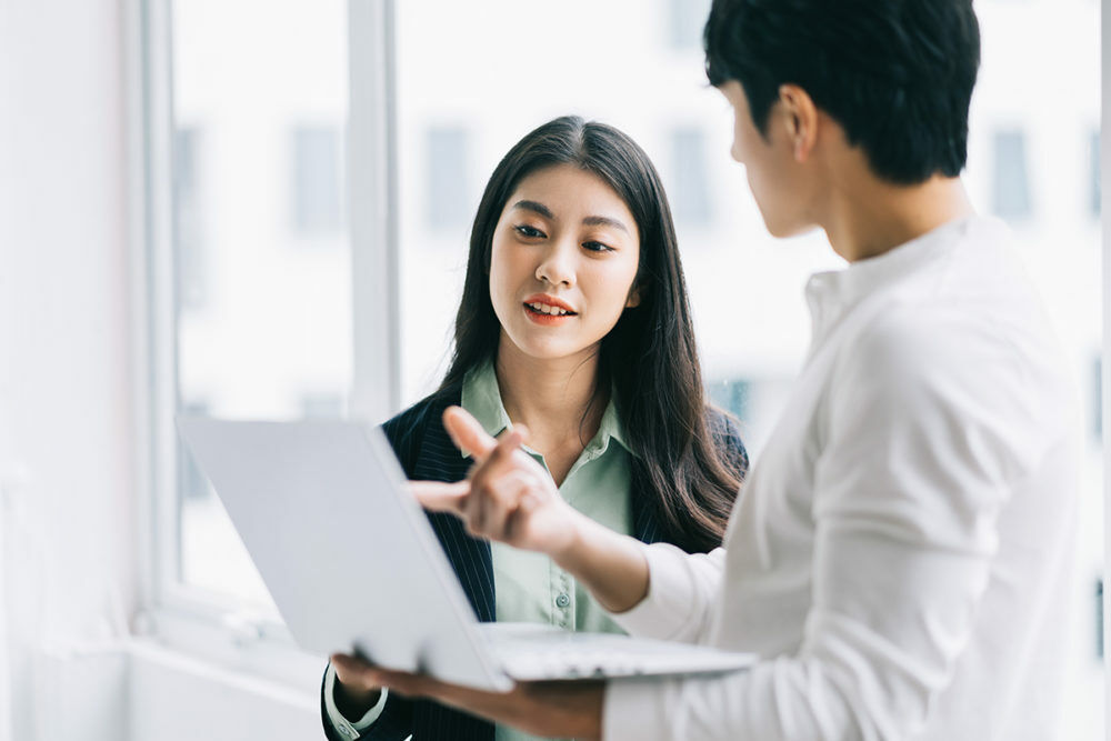 A girl is discussing with a man who pointing to the labtop